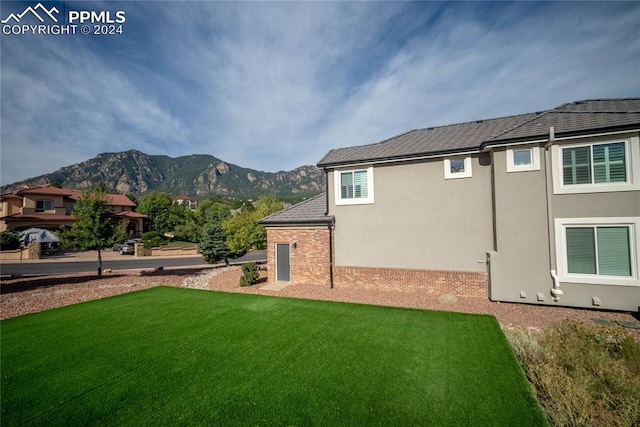 back of house with a yard and a mountain view