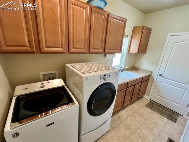 clothes washing area featuring washer and dryer, cabinets, and sink