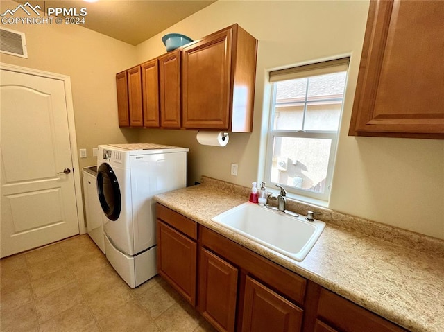 laundry room with cabinets, washing machine and dryer, and sink