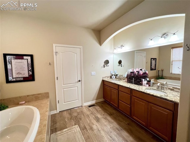 bathroom featuring vanity, hardwood / wood-style flooring, and tiled tub