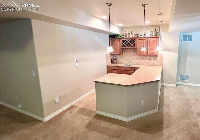 kitchen with decorative backsplash, decorative light fixtures, kitchen peninsula, and sink