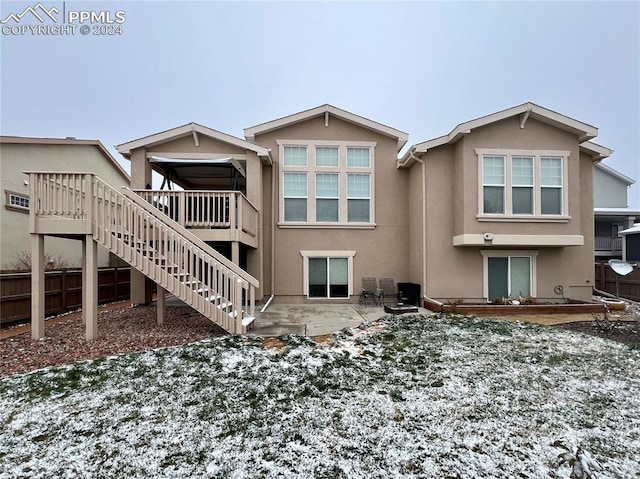 snow covered house featuring a patio and a deck