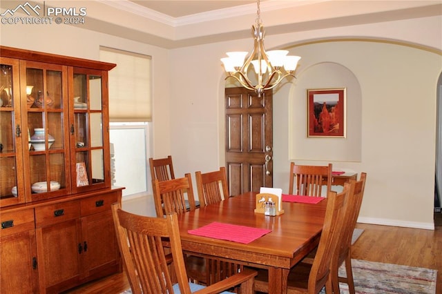 dining area featuring hardwood / wood-style floors, crown molding, and an inviting chandelier