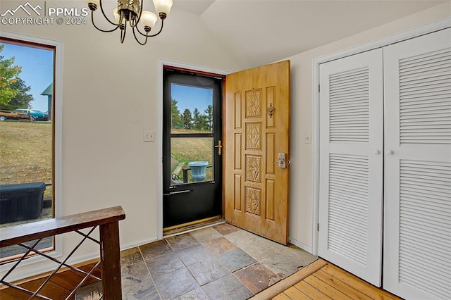 foyer entrance featuring an inviting chandelier and vaulted ceiling