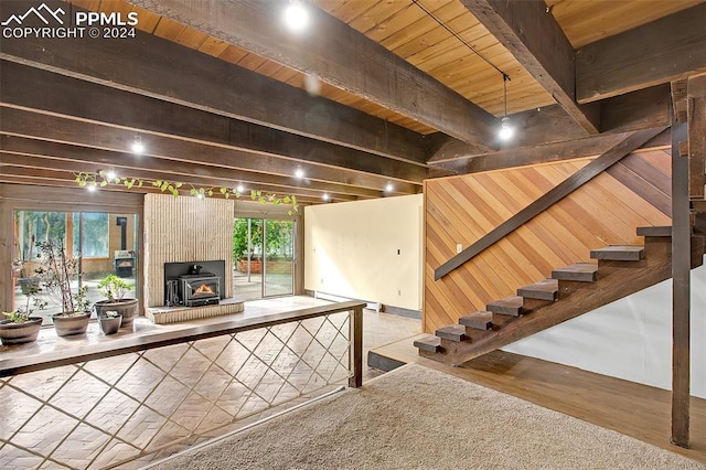 interior space with a wood stove, a healthy amount of sunlight, hardwood / wood-style floors, and a baseboard heating unit