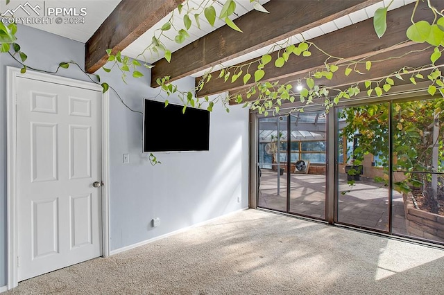 unfurnished living room featuring carpet floors and beam ceiling