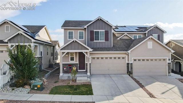 craftsman house with central air condition unit, solar panels, and a garage