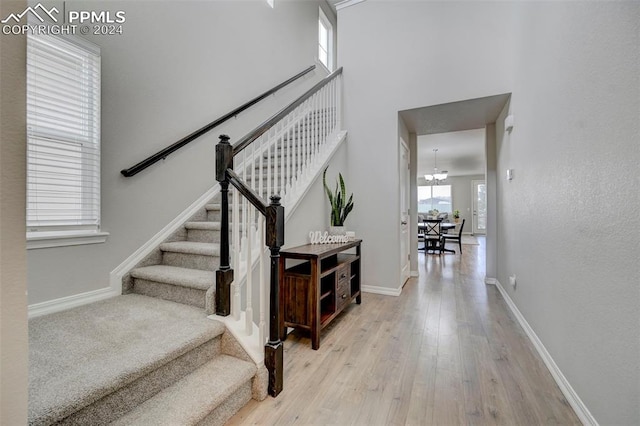 stairs with hardwood / wood-style flooring and a chandelier