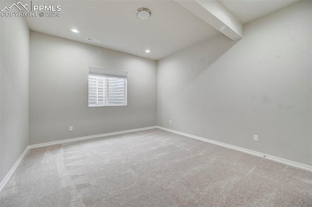 empty room featuring beam ceiling and carpet