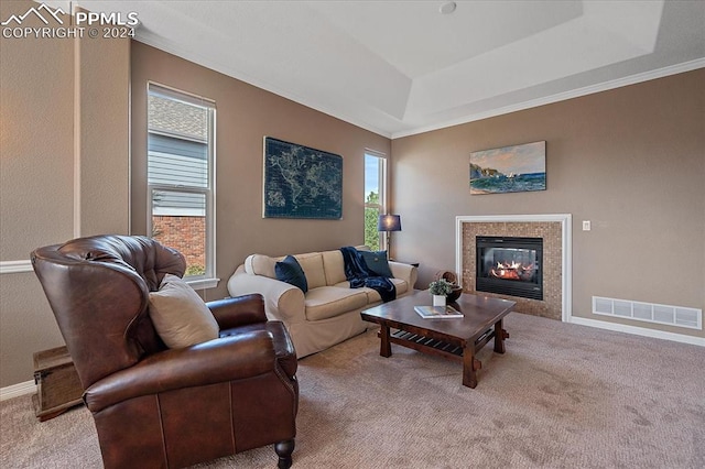 carpeted living room featuring crown molding, a tiled fireplace, and a tray ceiling