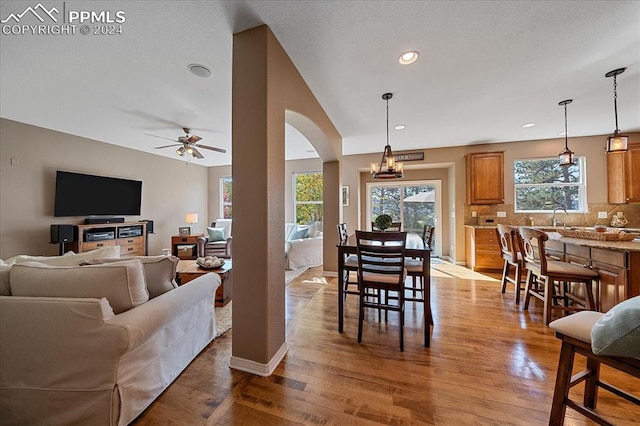 dining area with ceiling fan with notable chandelier, light wood-type flooring, and sink