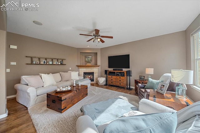 living room featuring a tile fireplace, ceiling fan, and hardwood / wood-style floors