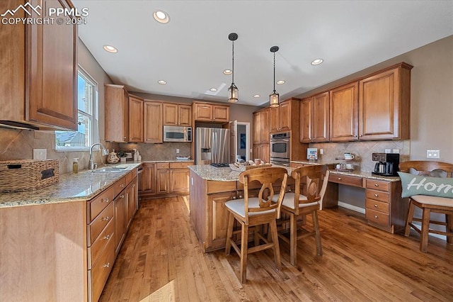 kitchen featuring sink, appliances with stainless steel finishes, a center island, light wood-type flooring, and decorative backsplash