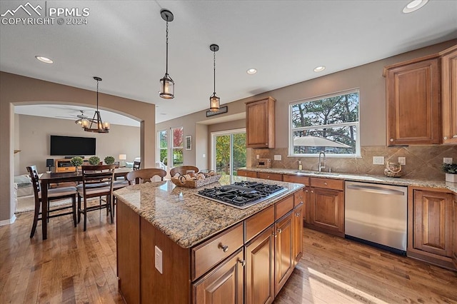 kitchen featuring sink, decorative light fixtures, stainless steel appliances, a center island, and light wood-type flooring