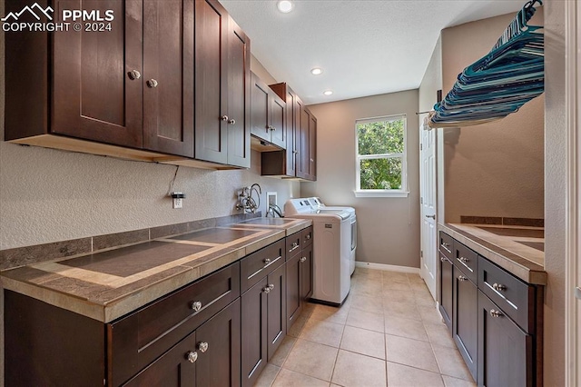 washroom featuring separate washer and dryer, sink, light tile patterned floors, and cabinets