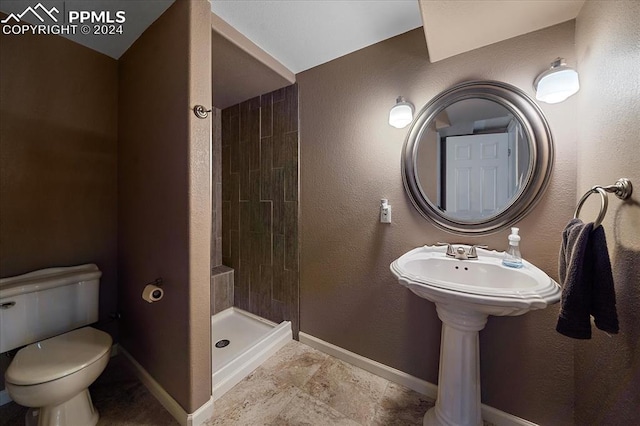 bathroom with a tile shower and toilet