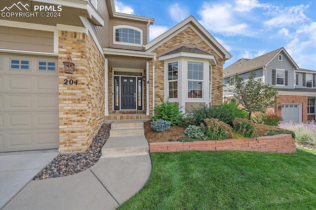 view of exterior entry featuring a garage and a lawn