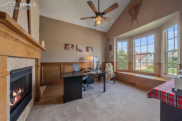 carpeted office space featuring ceiling fan, high vaulted ceiling, a fireplace, and plenty of natural light