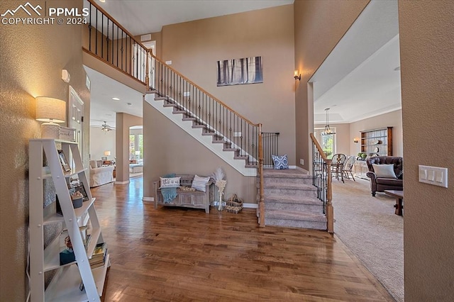 interior space featuring ceiling fan with notable chandelier, a towering ceiling, and wood-type flooring