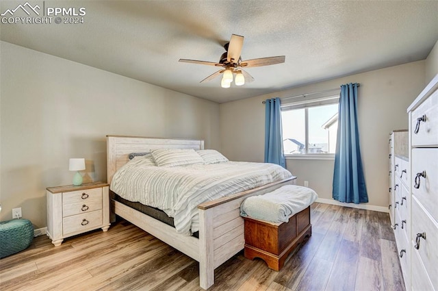 bedroom with light hardwood / wood-style floors, a textured ceiling, and ceiling fan