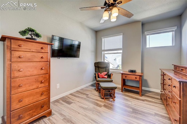 sitting room with a textured ceiling, light wood-type flooring, and ceiling fan