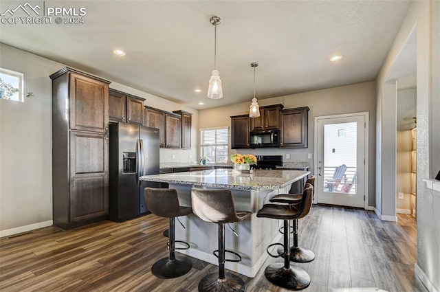 kitchen featuring black appliances, dark brown cabinets, dark hardwood / wood-style flooring, a center island, and hanging light fixtures