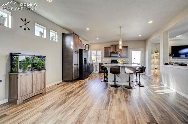 kitchen with a kitchen island, stainless steel appliances, light hardwood / wood-style floors, and plenty of natural light