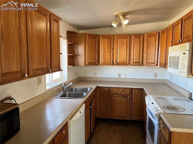 kitchen with lofted ceiling, white appliances, and sink