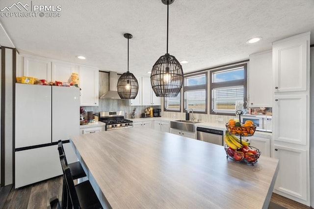 6652 Middlefield Ct, Colorado Springs, CO 80928 - kitchen with stainless steel appliances, wall chimney range hood, a sink, white cabinets, and a textured ceiling