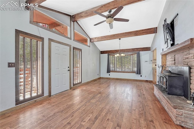 unfurnished living room with ceiling fan with notable chandelier, hardwood / wood-style flooring, beamed ceiling, and plenty of natural light