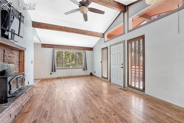 living room with ceiling fan, a wood stove, beam ceiling, and light hardwood / wood-style floors