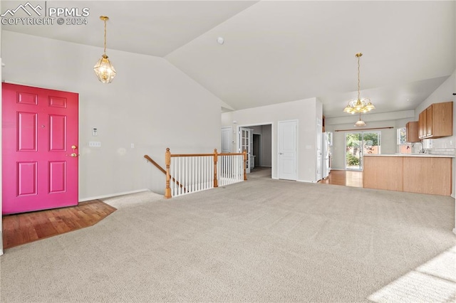 living room with a chandelier, vaulted ceiling, and light carpet