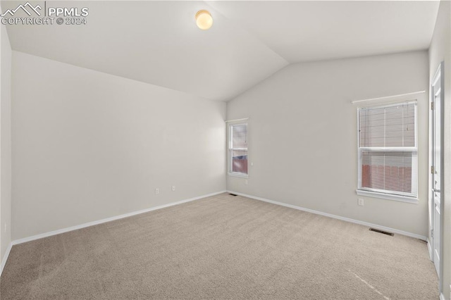 carpeted spare room featuring vaulted ceiling