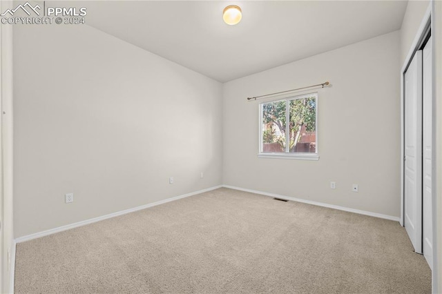 unfurnished bedroom with a closet and light colored carpet