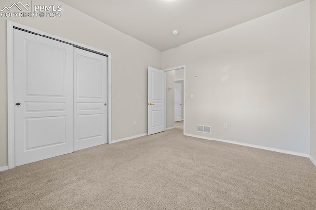 unfurnished bedroom with a closet and light carpet