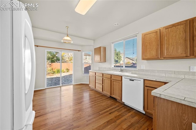 kitchen featuring white appliances, sink, hardwood / wood-style floors, and hanging light fixtures