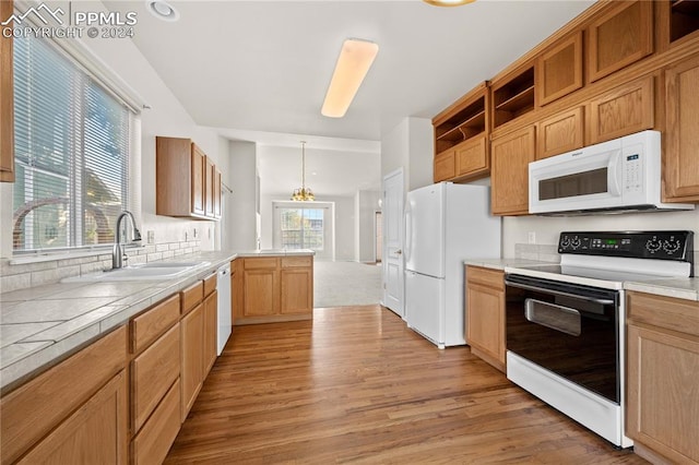 kitchen with white appliances, decorative light fixtures, light wood-type flooring, and sink