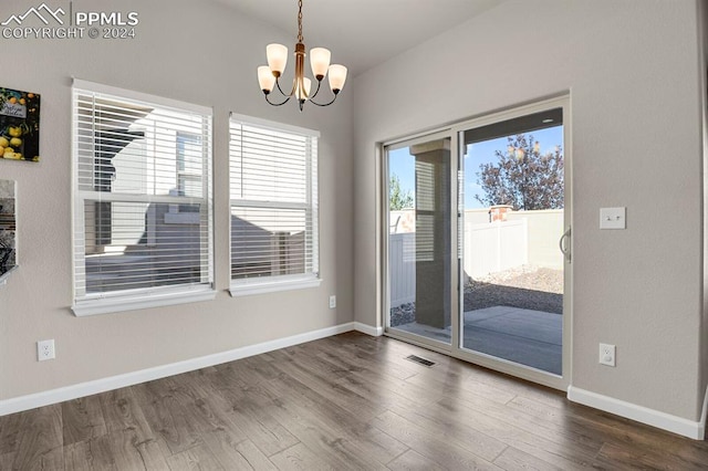 unfurnished dining area with dark hardwood / wood-style floors and a notable chandelier