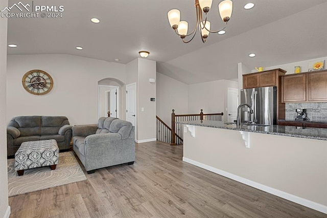 living room featuring a notable chandelier, lofted ceiling, and light hardwood / wood-style flooring