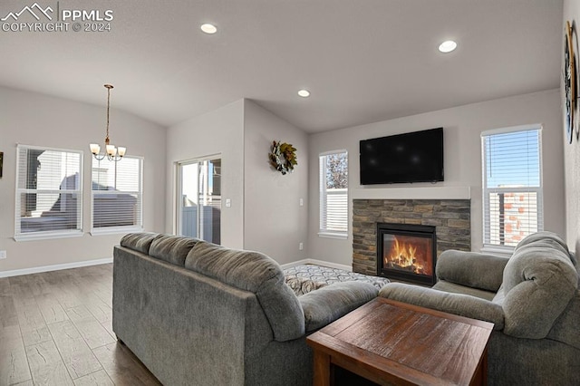 living room featuring a fireplace, light hardwood / wood-style flooring, a chandelier, and plenty of natural light