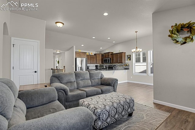 living room with dark wood-type flooring, an inviting chandelier, and lofted ceiling