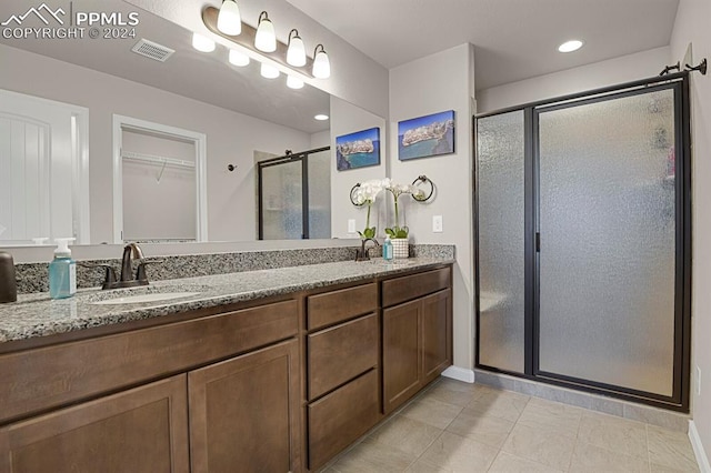 bathroom featuring tile patterned flooring, vanity, and a shower with shower door