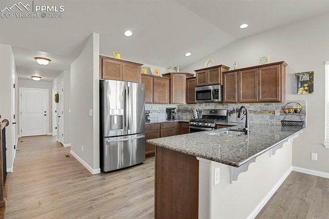 kitchen featuring backsplash, sink, dark stone countertops, kitchen peninsula, and stainless steel appliances