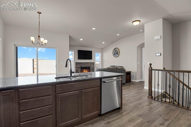 kitchen with a healthy amount of sunlight, stainless steel dishwasher, a stone fireplace, and sink