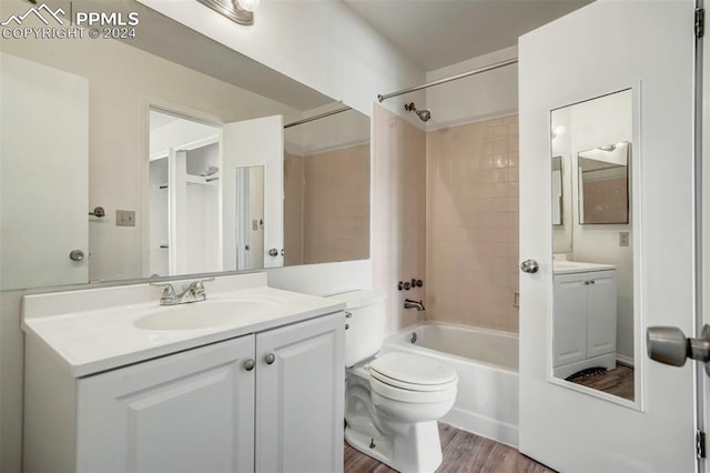 full bathroom featuring tiled shower / bath, vanity, wood-type flooring, and toilet