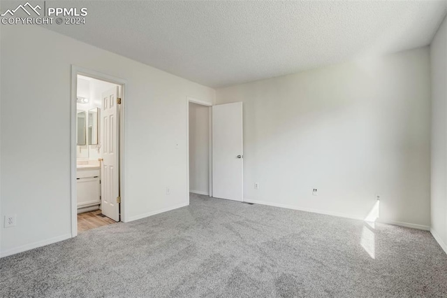 unfurnished bedroom featuring a textured ceiling and connected bathroom