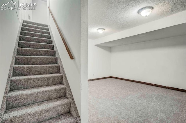 stairs featuring a textured ceiling and carpet