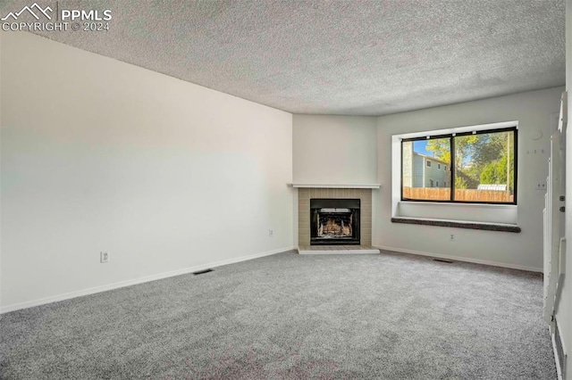 unfurnished living room with a textured ceiling, carpet flooring, and a brick fireplace