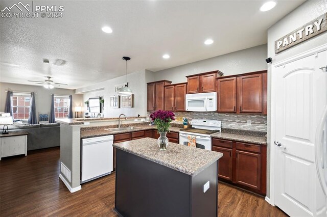 kitchen featuring dark wood-style flooring, tasteful backsplash, a sink, white appliances, and a peninsula