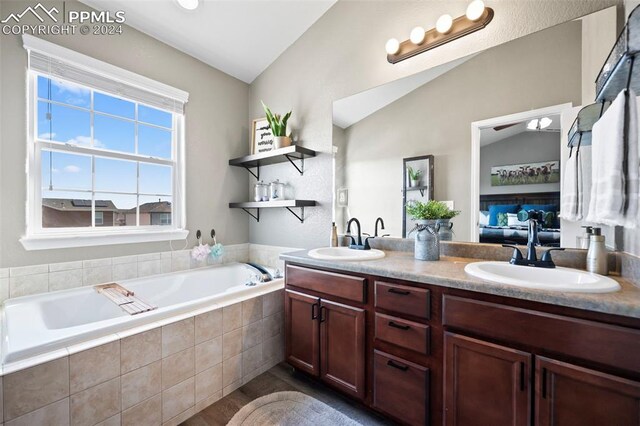 ensuite bathroom featuring lofted ceiling, ensuite bath, a sink, and a garden tub